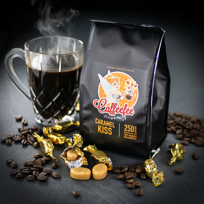 Abbildung Packung Caffeefee Caramel Kiss. Daneben eine Tasse heißer Kaffee und drum herum verteilt Karamellbonbons und Kaffeebohnen.